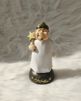 تمثال زينة رمضان كريم، شخصية كرتونية بثوب أبيض وعمامة ذهبية تحمل نجمة، قاعدة سوداء مزينة بنجوم ونص رمضان كريم، ديكور إسلامي